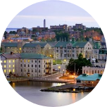 Buildings on the waterfront in Kingston, Canada, with more city buildings cascading behind it.