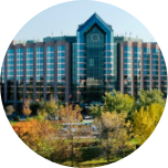 Large building with lots of windows in Markham, Canada, and green trees in the forefront.