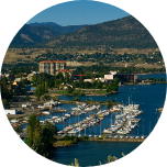 A harbour scene in Penticton (Canada), with boats in the harbour, green hills and mountains in the background.