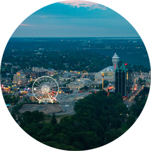 Niagara Falls city scene at dusk, with a lit up ferris wheel in the centre and other lit up buildings surrounding it.