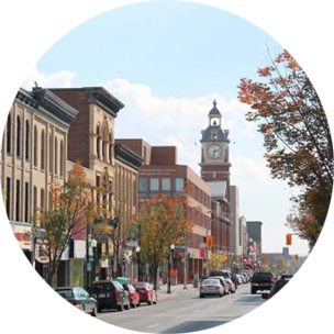 A main street running through Peterborough, Canada, with large buildings and a tall clock tower lining the street.