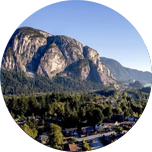 An area of large green Canadian tress leading up to Rocky mountains in Squamish, Canada.