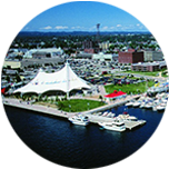 A harbour with white boats at the forefront, and lots of buildings behind it in Sault Ste Marie, Canada.