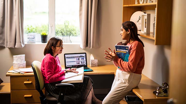 Two women talking in a room while studying for the IELTS