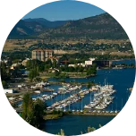 A harbour scene in Penticton (Canada), with boats in the harbour, green hills and mountains in the background.