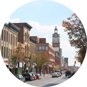 A main street running through Peterborough, Canada, with large buildings and a tall clock tower lining the street.